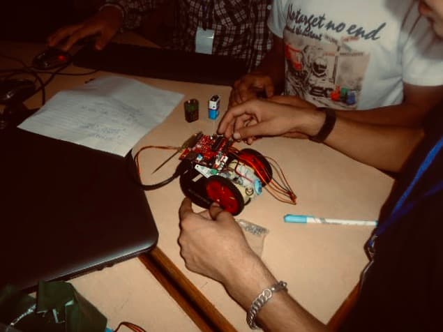 Hands assembling and testing a small wheeled robotics prototype during an engineering activity